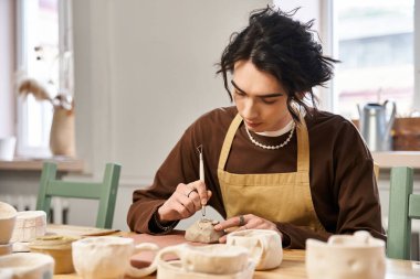 Şık bir adam sanatsal aletler ve kreasyonlarla dolu parlak bir stüdyoda kil şekillendirir..