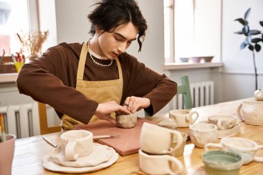 Yakışıklı bir adam, stüdyodaki güzel seramik kreasyonlarla çevrili killeri şekillendirmeye odaklanmış..