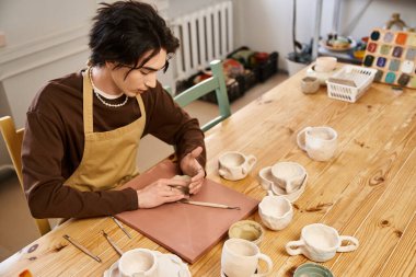 Becerikli bir sanatçı, el yapımı çömlek araçlarıyla çevriliyken kili zarif formlara dönüştürür..