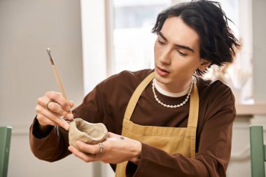 Sanatçının elleri, parlak bir stüdyoda özenle çömlek tasarlarken açılır..