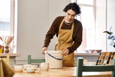 Yetenekli bir adam sanatsal malzemeler ve aletlerle çevrili iken tutkuyla çömlek üzerinde çalışır..