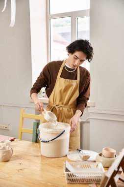 Çömlek atölyesinde yakışıklı bir adam bir sonraki seramik eseri için malzemeleri ustalıkla hazırlıyor..