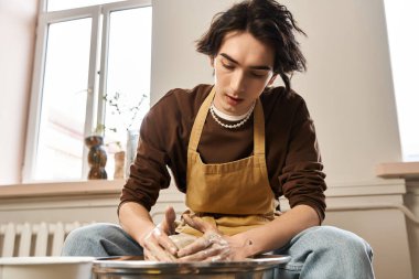 Yaratıcı adam, iyi aydınlatılmış ve ilham verici bir çömlek atölyesinde çamuru şekillendirmeye özen gösterir.