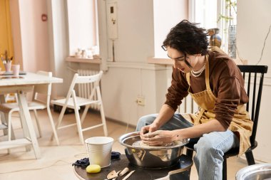 Yakışıklı bir adam parlak, ilham verici bir stüdyoda çömlek çarkında kil şekillendirir..