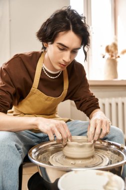Şık bir genç adam yaratıcı bir çalışma alanında çömlek çarkında kil şekillendirir..