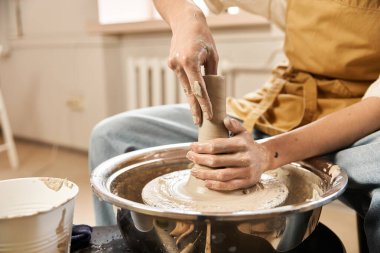 Yakışıklı bir adam, sanat eserleriyle dolu ilham verici bir stüdyoda çömlek çarkında kil kalıplarını ustalıkla şekillendiriyor..