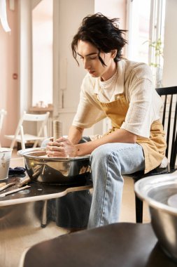 Yakışıklı bir adam, bir stüdyonun canlı atmosferine dalmış vaziyette çömlek yapıyor..