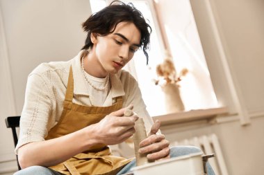 Yakışıklı ve şık bir adam, yaratıcılıkla dolu parlak bir çömlek atölyesinde kil şekillendirir..