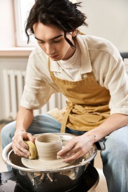 Şık bir adam çömlek çarkında kil şekillendiriyor, sanatsal sürecine dalmış..