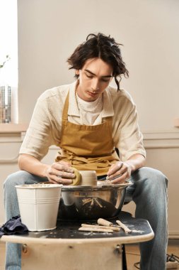 Yetenekli bir adam, canlı bir stüdyoda sanat malzemeleri ve aletleri arasında çömlek yapıyor..