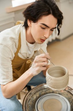 Yakışıklı, şık bir adam, parlak bir stüdyoda eşsiz bir çömlek yapmaya odaklanıyor..