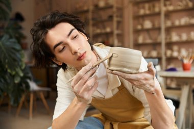 Yetenekli bir sanatçı, canlı bir çömlek atölyesinde seramik bir parçayı şekillendirirken dikkatle odaklanır..