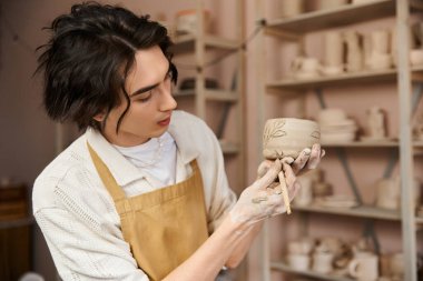 Çömlek atölyesindeki yakışıklı bir adam yaratıcılığını ve yeteneklerini sergileyerek killeri özenle şekillendirir..