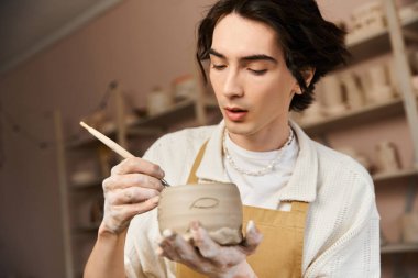 Şık bir adam, parlak bir çömlek atölyesinde killeri titizlikle şekillendiriyor ve yaratıcılığını sergiliyor..