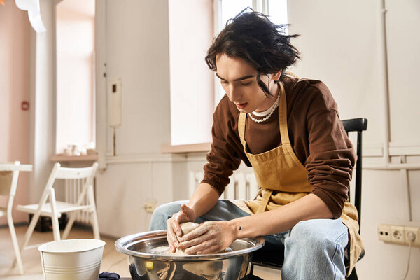 A handsome man skillfully molds clay in a vibrant, creative pottery studio.