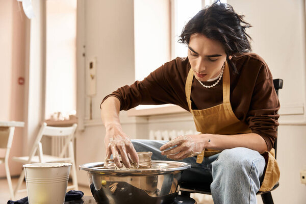 A handsome man is focused on crafting pottery in a bright and airy ceramics studio.