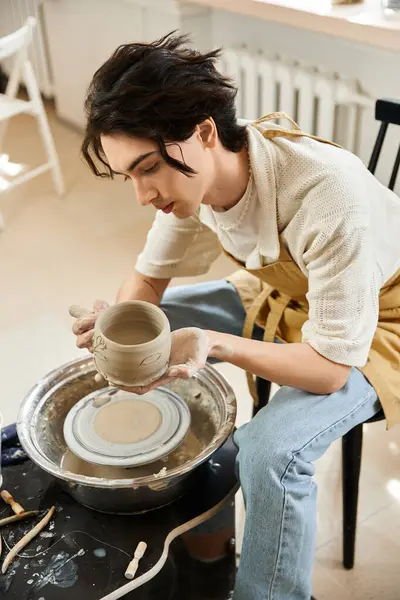 Yaratıcı adam, sanat eserleriyle çevrili çömlek atölyesinde, tekerleğin üzerinde kil tencereyi ustalıkla şekillendirir..