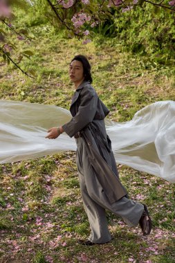 Sakin bir parkta, gri giyen genç bir adam polietilen, sürdürülebilirlik konseptiyle etkileşime girer.