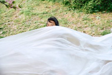 Şık gri kıyafetli genç bir adam yeşil bir parkta polietilen ile poz veriyor..