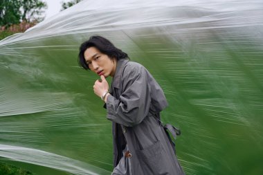 Genç Asyalı bir adam parkın içinde dolaşır, kendine güveni tamdır..