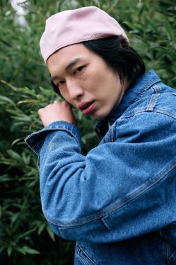 Genç bir adam şık kot kıyafetlerini güzel bir park ortamında sergiliyor, doğanın tadını çıkarıyor..