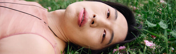 A young asian man lies back in a park, enjoying the moment, banner