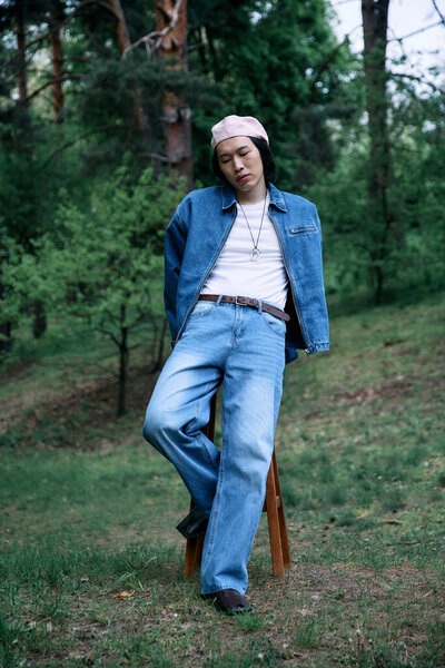 A young man relaxes in the park, blending casual fashion with natural confidence.