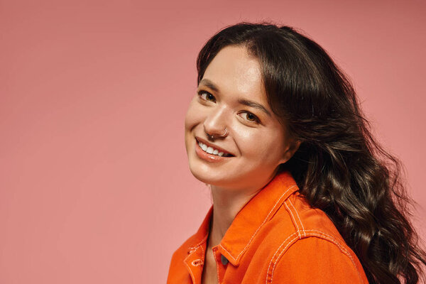 Charming young woman in stylish attire smiles brightly, radiating warmth.