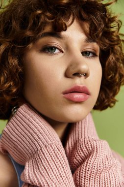 Genç bir kadın şık bir kıyafet ve kısa kıvırcık saçlarıyla gösteriş yapar..