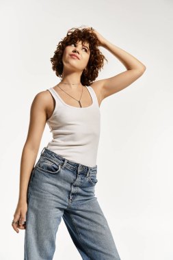 Kıvırcık saçlı genç bir kadın yaz mevsiminde kolsuz bluz ve kot pantolon giyer..