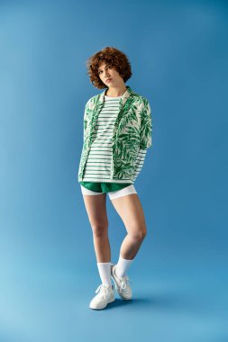 Canlı bir yaz kıyafeti içindeki genç bir kadın parlak mavi bir arka plana karşı duruyor..