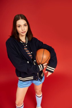 Genç ve güzel bir kadın, elinde basketbol topuyla moda anlayışını ifade ediyor..