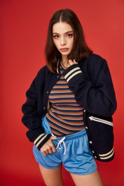 Genç kadın renkli çizgili ve koordine şortlu modaya uygun kıyafetleri stüdyoda sergiliyor..