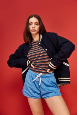 Kendine güvenen, modaya uygun giyinmiş genç bir kadın cesur bir arkaplanda parlıyor..