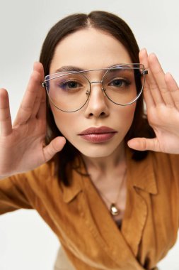 Şık giyinmiş genç bir kadın. Elleri yüzüne yakın poz veriyor. Göz rengini açıyor..