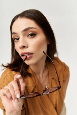 Kendinden emin genç bir kadın canlı kıyafetini sergiliyor ve şık bir şekilde gözlüklerini tutuyor..