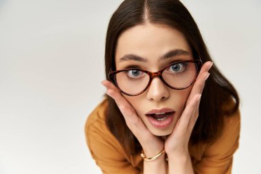 Cesur giyinmiş güzel bir kadın, şaşkın bir şekilde poz veriyor..