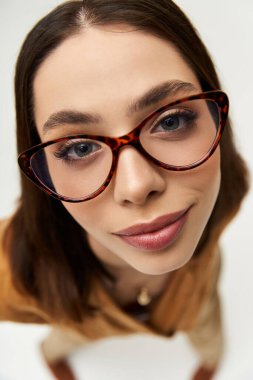 Kendine güvenen genç kadın şık bir görünüş için canlı moda ve şık gözlükler sergiliyor..