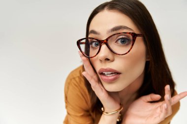 Güzel hatları olan genç bir kadın şık kıyafetinin ve eşsiz gözlüklerinin altını çiziyor..