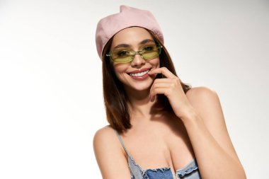 Genç bir kadın ışıl ışıl gülümser, enerjik moda seçimlerini oyuncu bir özgüvenle gösterir..