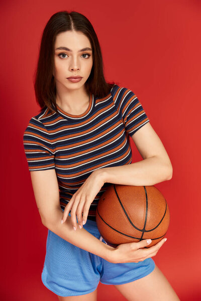 Young woman in trendy attire holds a basketball, showcasing her fashionable style and confidence.