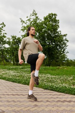 Sakallı genç bir adam dışarıda spor yapıyor, spor ve sağlığa odaklanıyor..