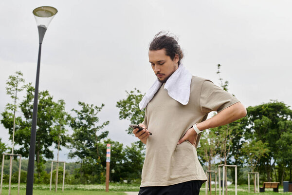 Молодой человек с бородой занимается спортом на открытом воздухе, оценивая свой прогресс во время тренировки.