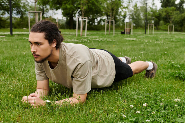 Caucasian man with a beard focuses on maintaining a plank position on lush grass outdoors.