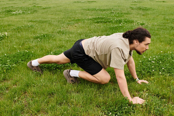 Молодой человек с бородой интенсивно тренируется на травянистой земле, демонстрируя ловкость и силу.