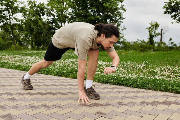 Молодой человек с бородой работает на дорожке, проверяя свои часы во время тренировки.