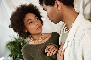 Çiftler birbirlerine sevgiyle bakar, yemyeşil bitkiler ve yumuşak ışıklarla çevrili..