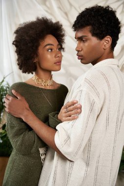 İki genç aşık, nazik ve yumuşak bir ışıkta samimi bir bakışı paylaşıyor..