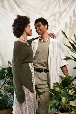 Sevgi dolu bir çift, sıcak, bitki dolu bir atmosferde kucaklaşırken birlikte güler..