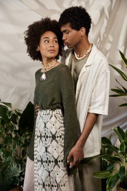 Şık bir çift, canlı bitkiler ve yumuşak ışıkla çevrili, samimi bir andan zevk alır..